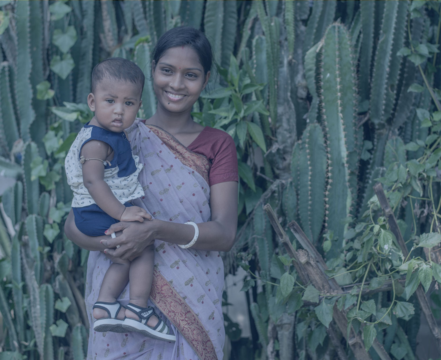 방글라데시 엄마 조야가 아이를 앉고 해맑게 웃고 있다.